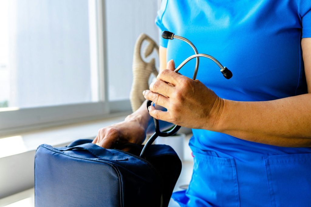 Eine Frau in einem blauen OP-Anzug, die ein Stethoskop hält.